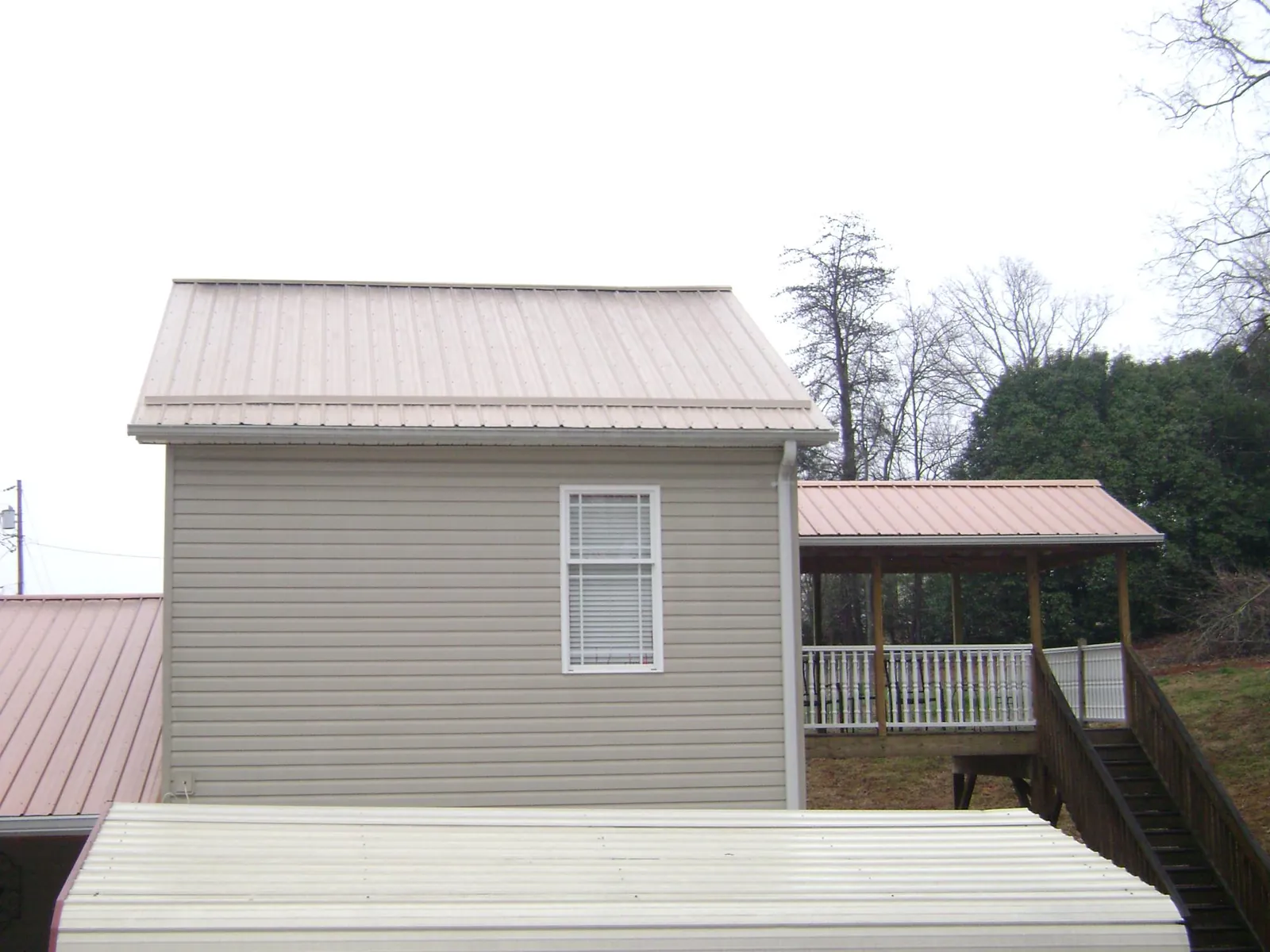 Tan metal roofs on a two story addition and attached porch, from a Roof Replacement job in Markham